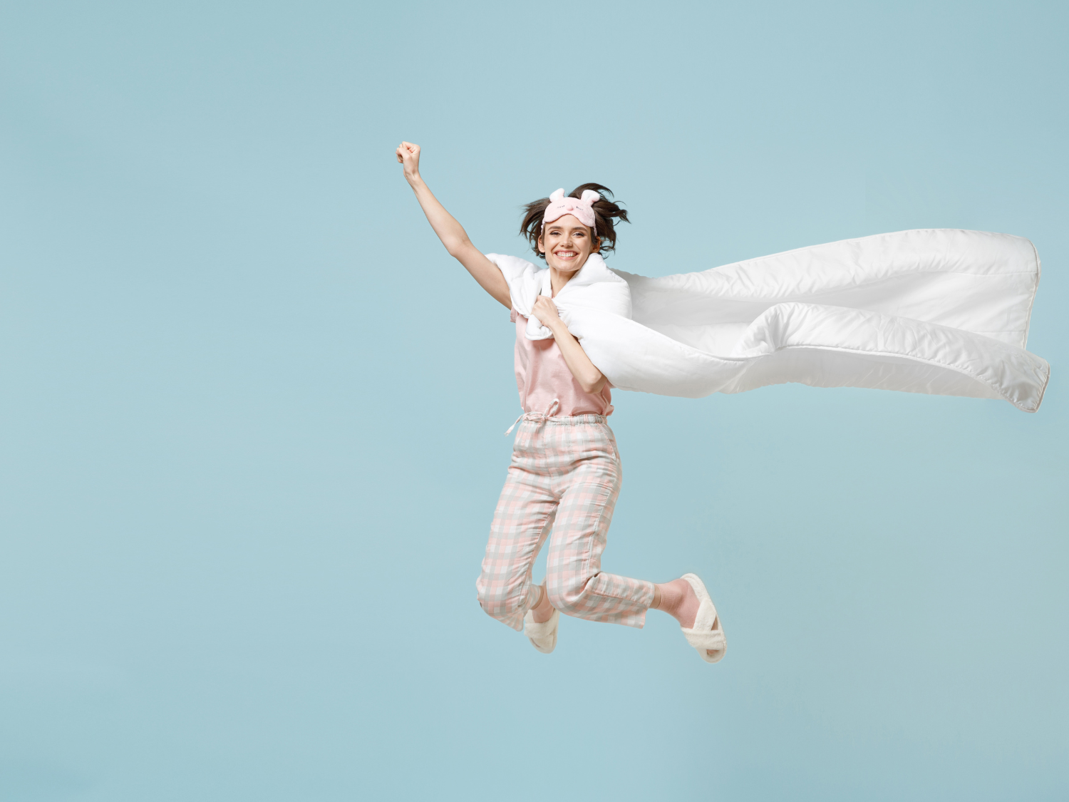 Frau springt mit Bettdecke in die Höhe