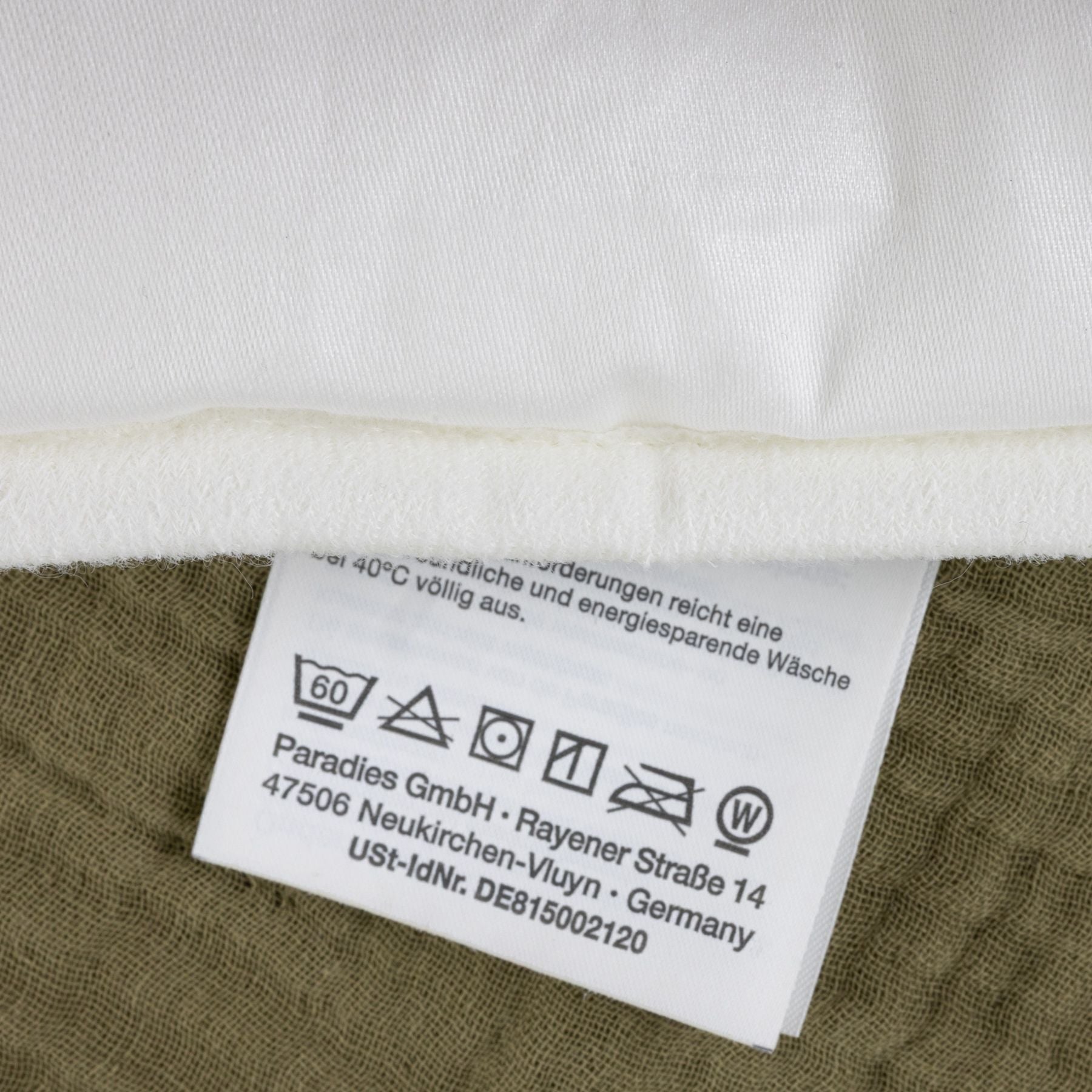 Pflegehinweise auf einem weißen Textil-Etikett mit Waschsymbolen und Herstellerangaben von Paradies