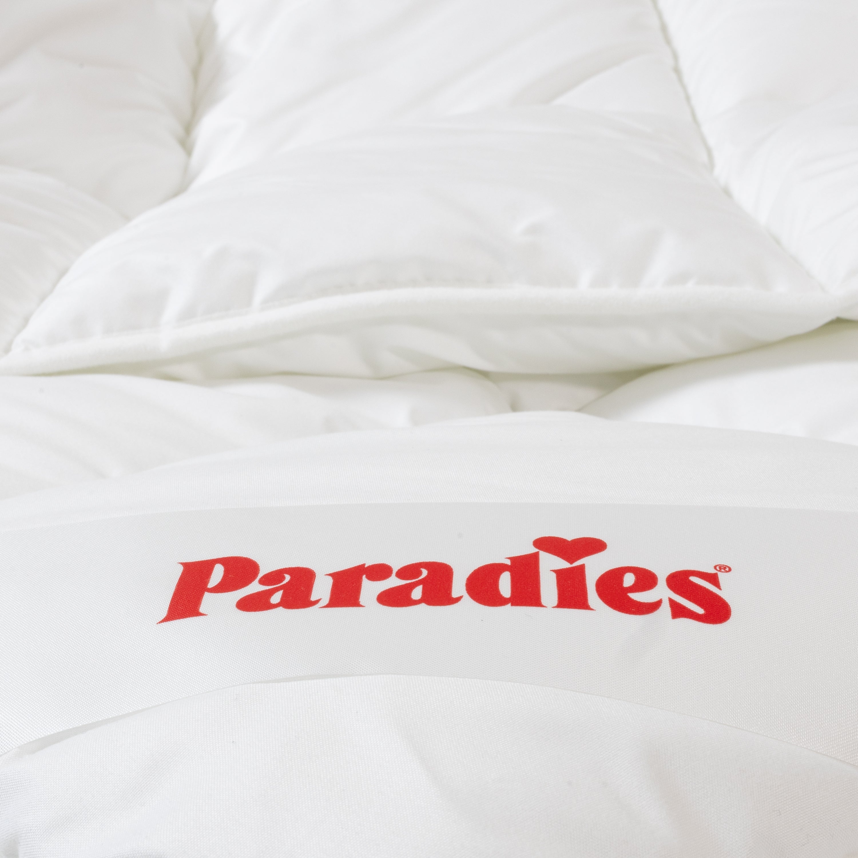Detailaufnahme der gefalteten Ganzjahresdecke Renova mit rotem Paradies-Logo auf dem Etikett