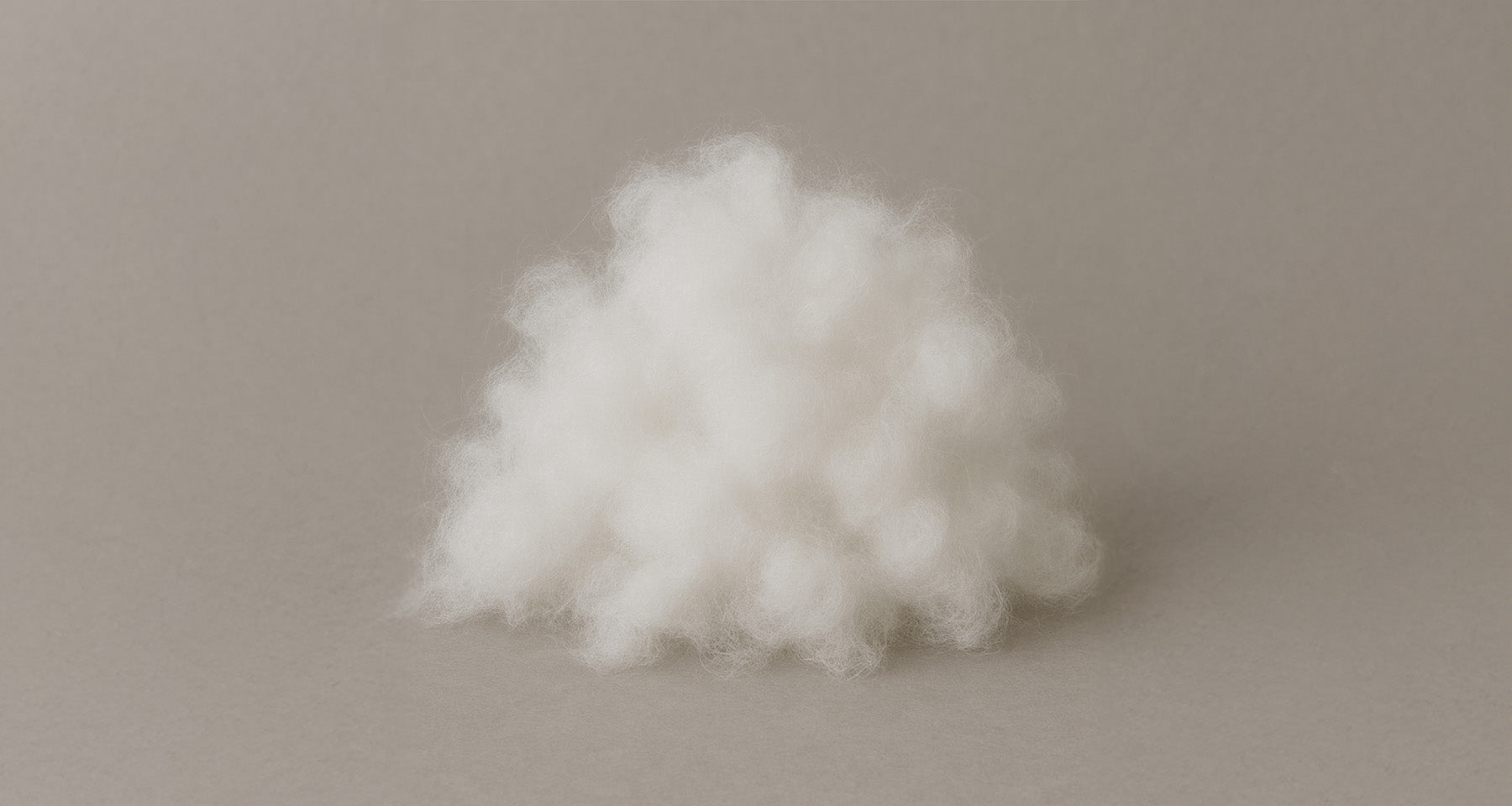 Haufen weißer, flauschiger Textilfasern auf grauem Hintergrund