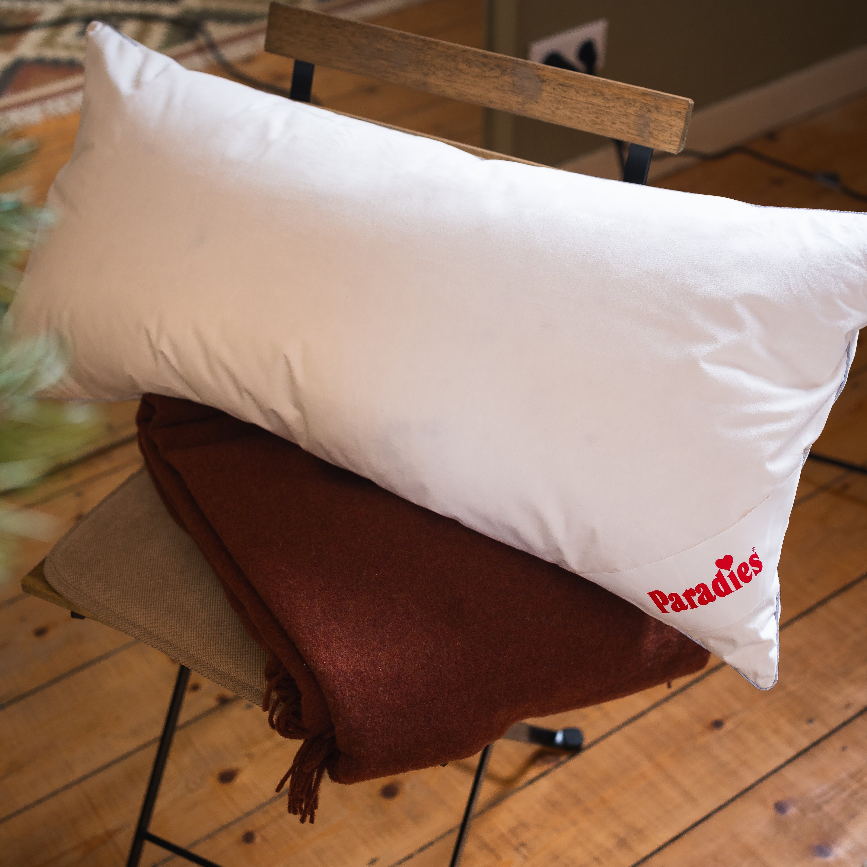 Weißes Paradies Kopfkissen, Größe 40x80 cm, liegt auf brauner Decke auf Stuhl