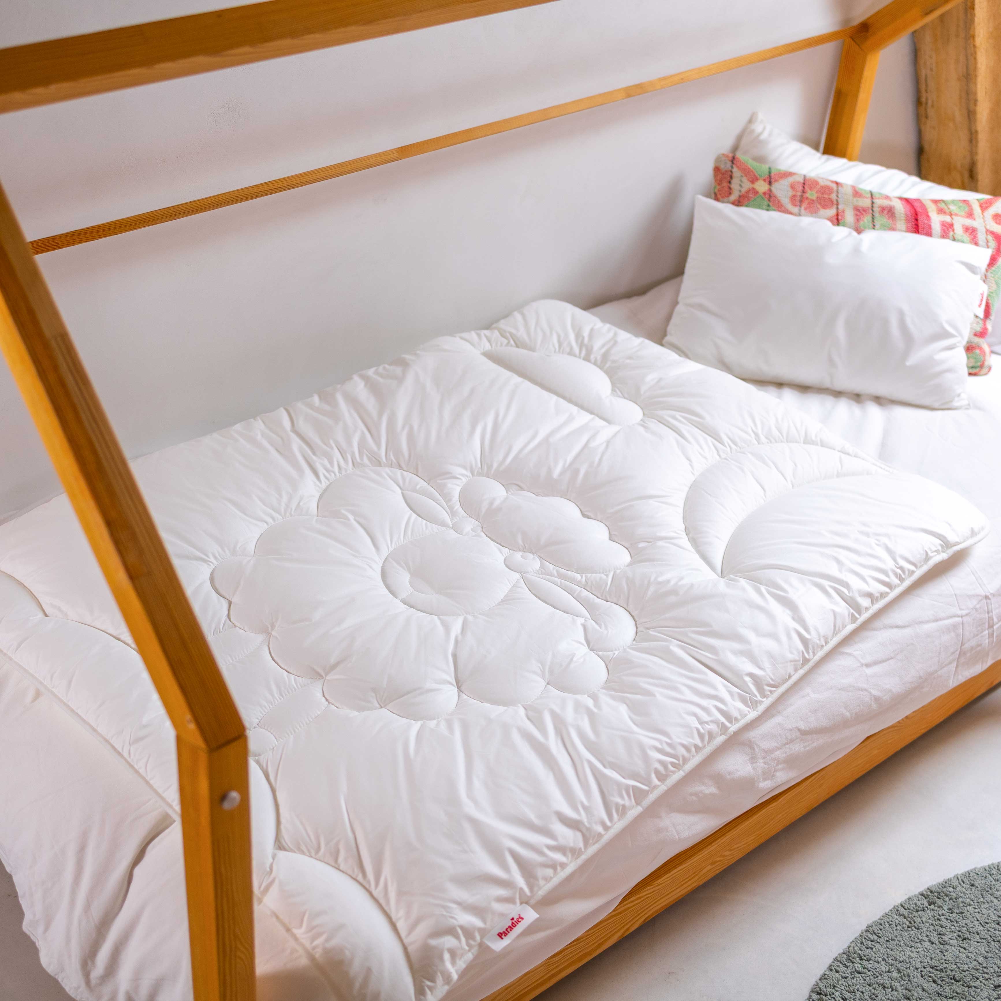 Bett mit Holzrahmen, weißer Steppdecke mit kreisförmigem Muster und mehreren Kissen